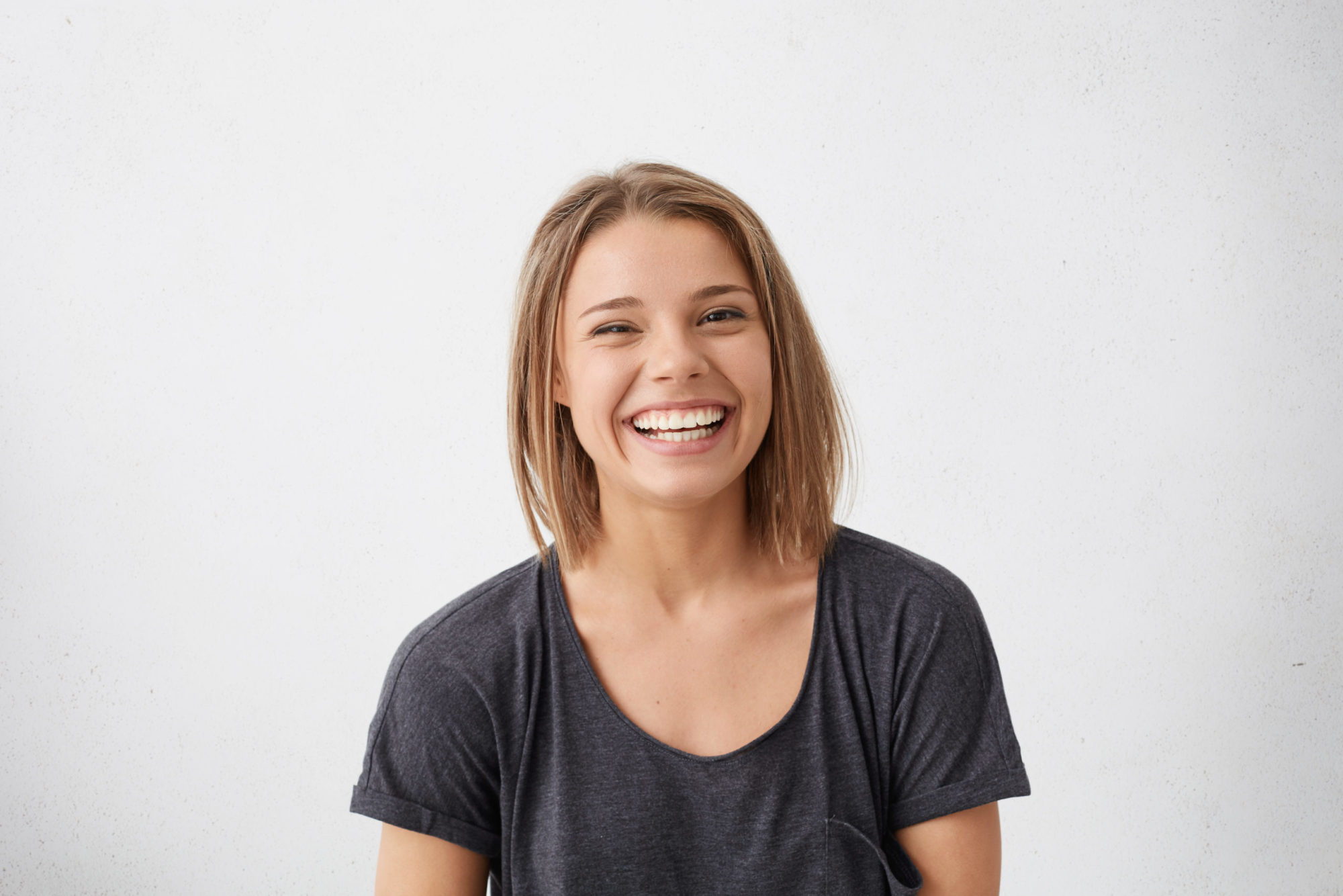 Smiling young woman with straight teeth, representing the benefits of orthodontic treatment and clear aligners for achieving a beautiful smile.